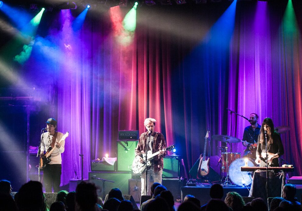 Band performing on stage with colorful lights.