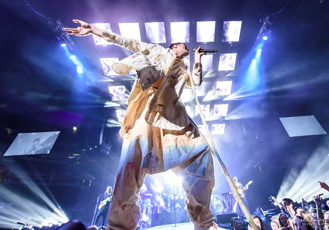 Concert performer singing energetically on stage.