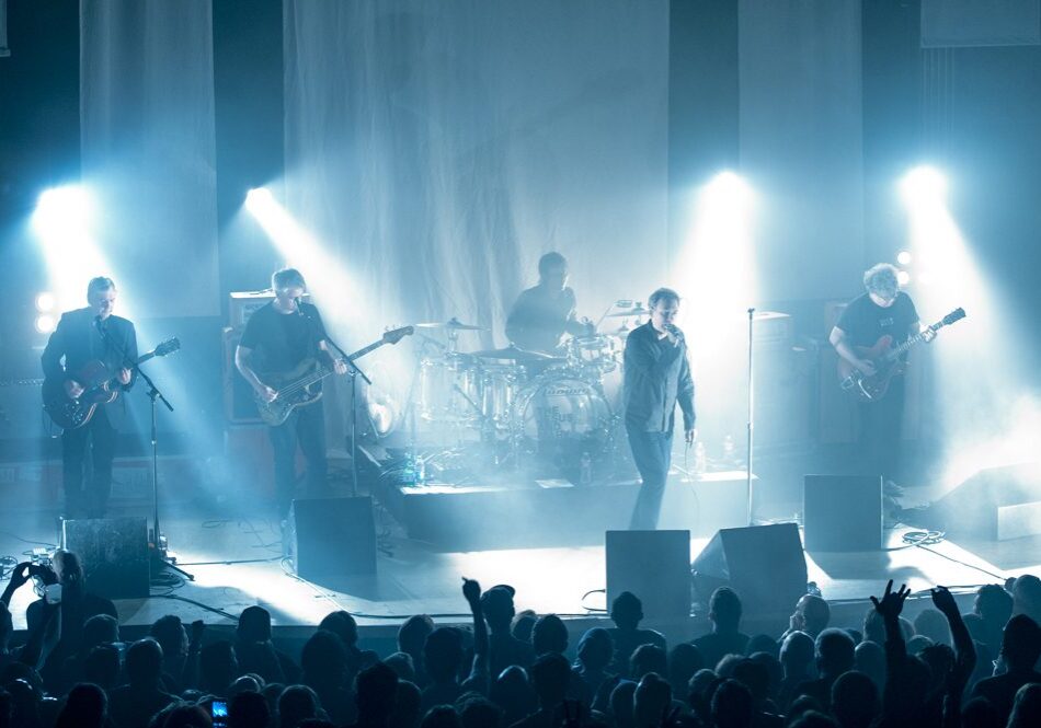 Band performing on stage with bright lights.