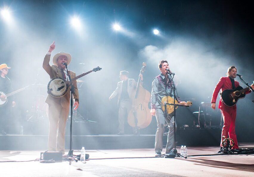 Band performing on stage with various instruments.