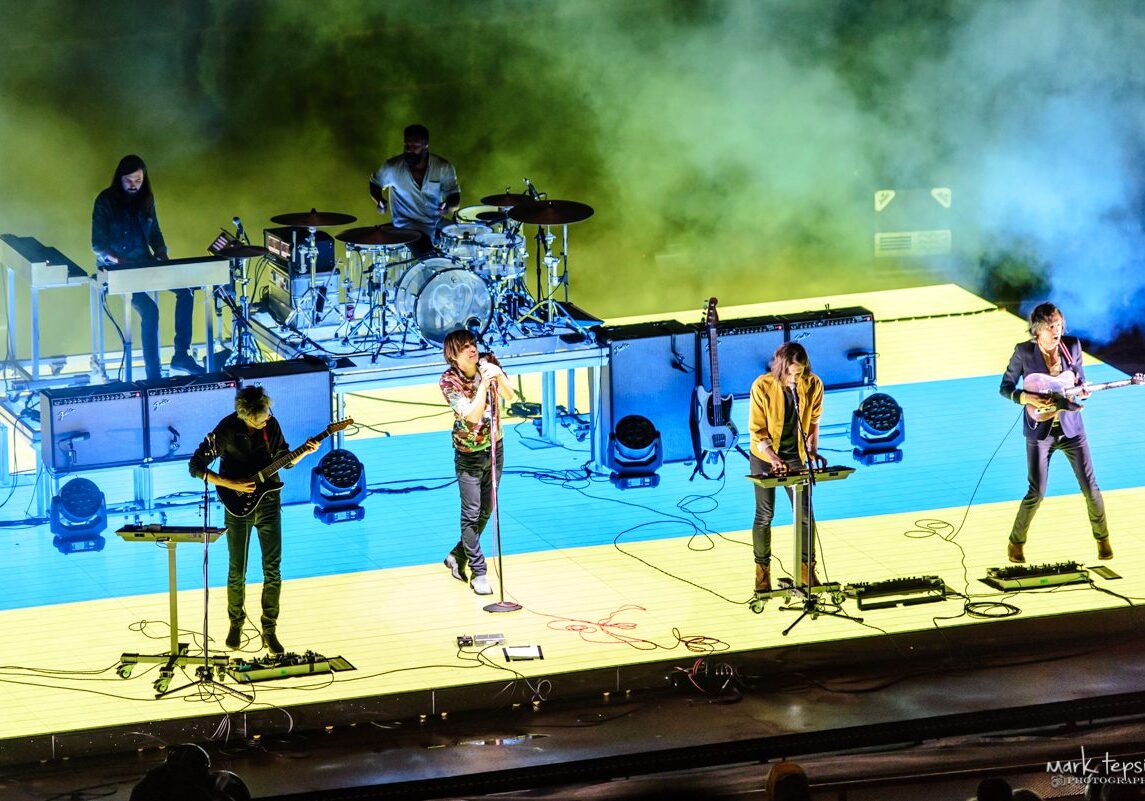 Band performing on stage with colorful lighting.