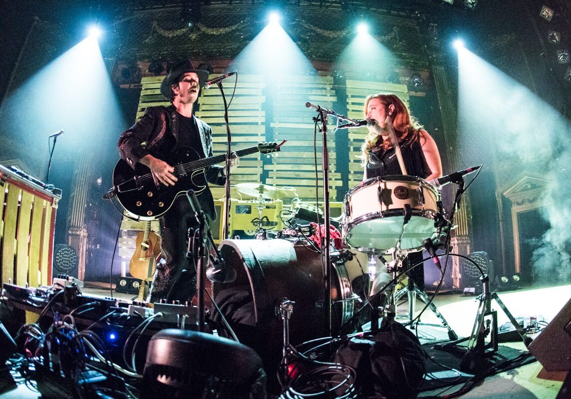Musicians performing energetically on stage with instruments.