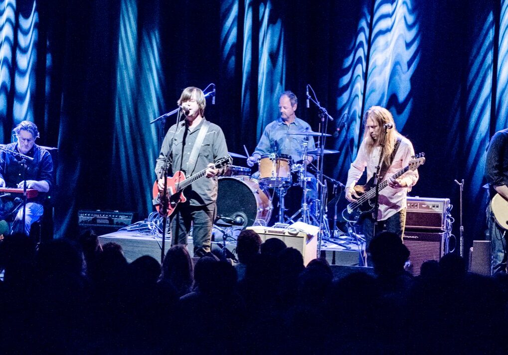Band performing live on stage with instruments.