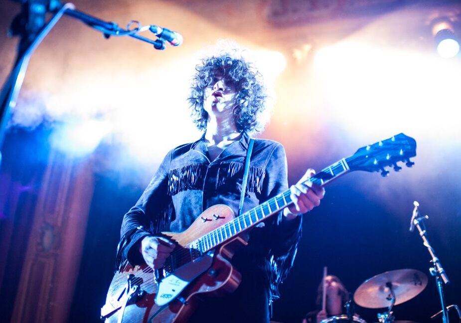 Musician performing with guitar under bright lights.