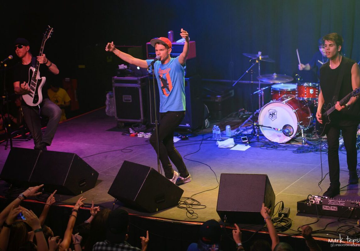 Band performing live on stage with instruments.