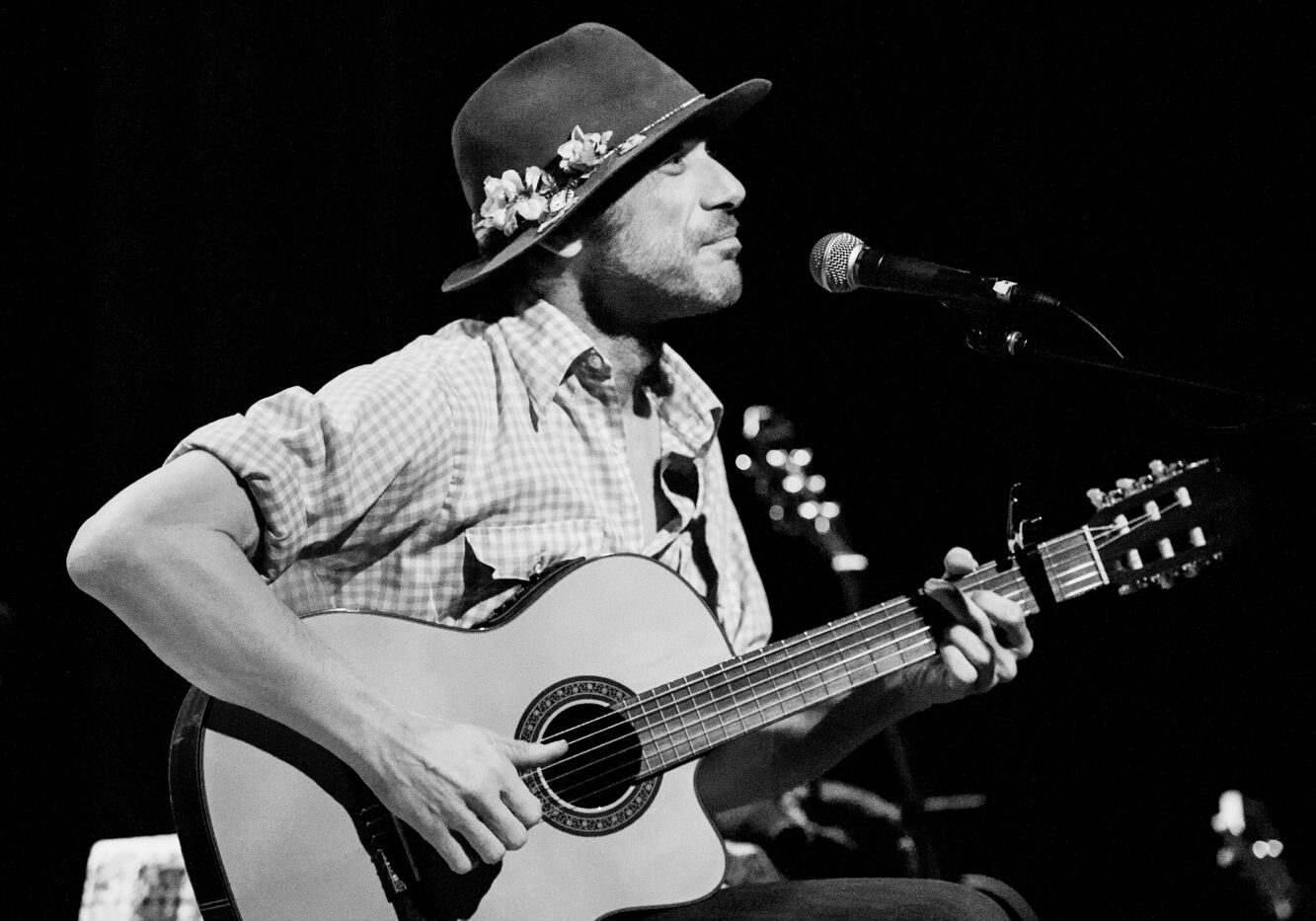 Musician playing guitar and singing on stage.