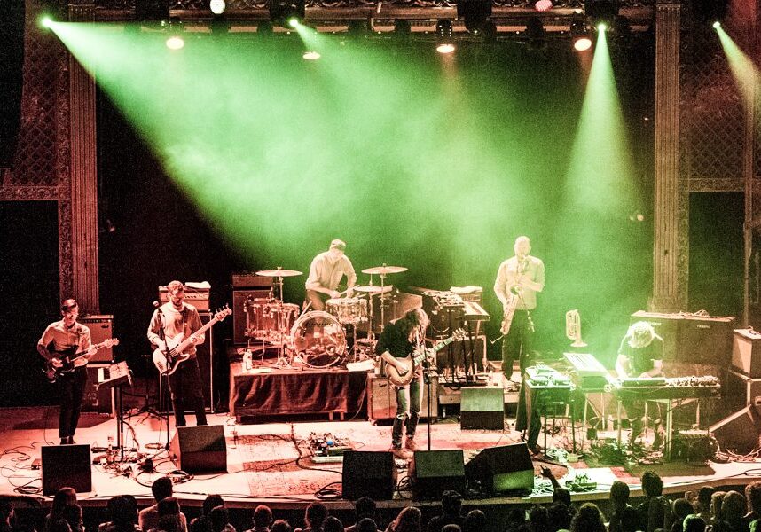 Band performing on stage with green lighting.