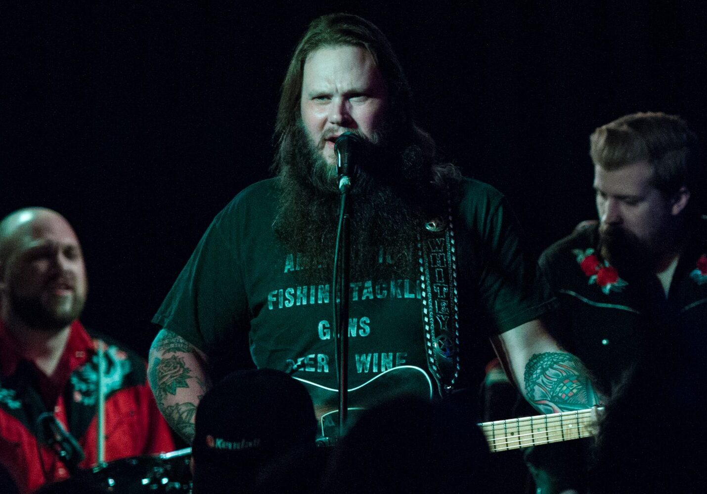Musician performing with guitar on stage.