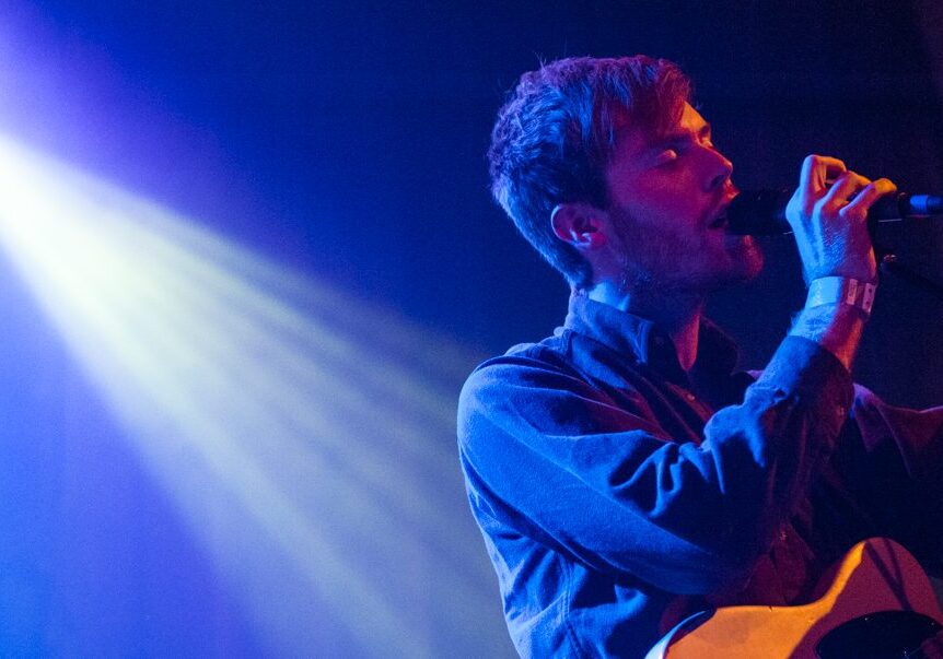 Singer performing on stage with guitar.