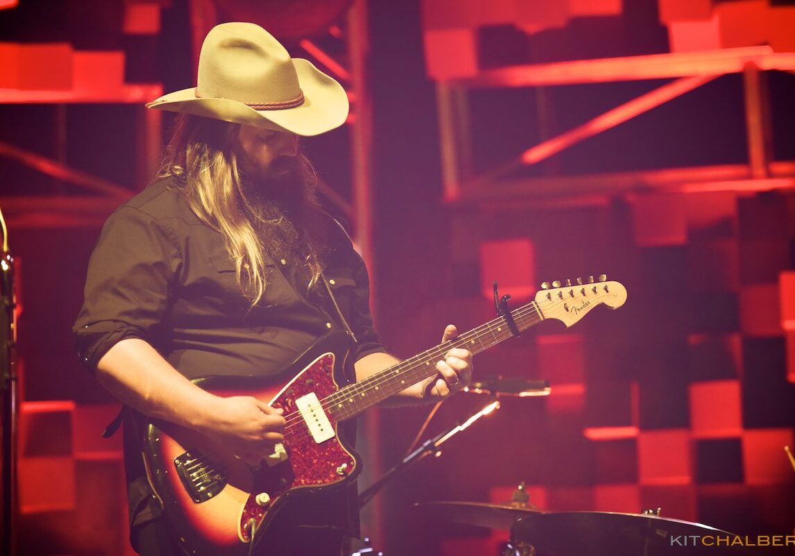 Musician playing electric guitar on stage.