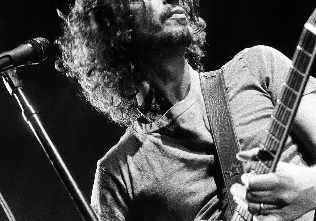 Musician playing guitar on stage, dramatic lighting.
