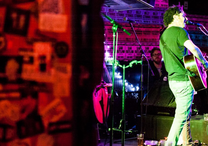 Musician performing live on stage with guitar.