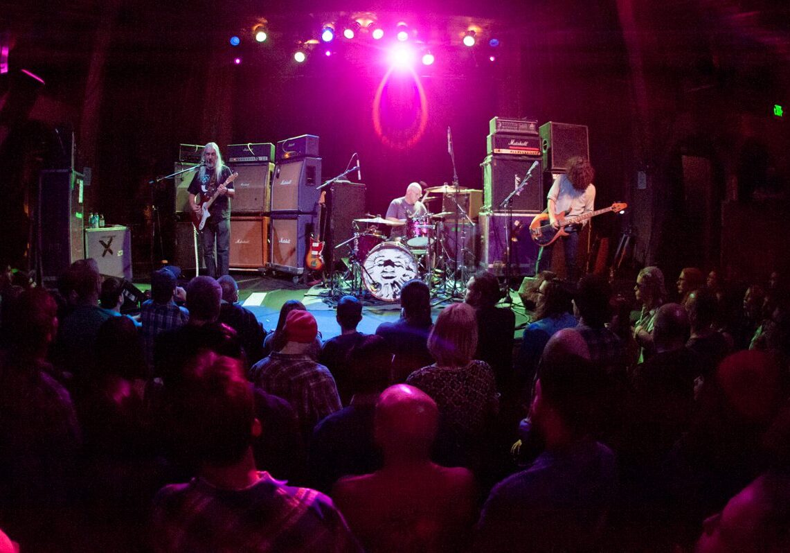 Rock band performing on stage with audience.
