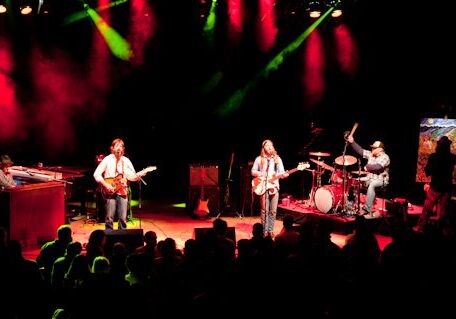 Band performing on stage with colorful lights.
