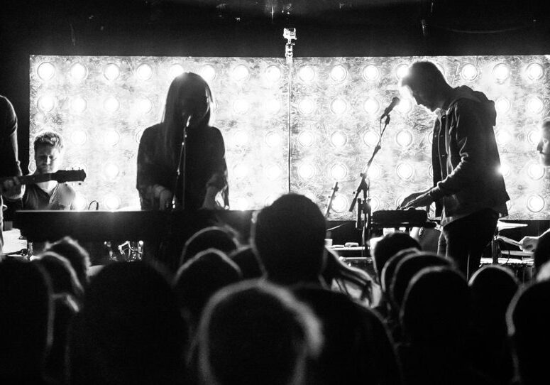 Band performing on stage with bright lights.