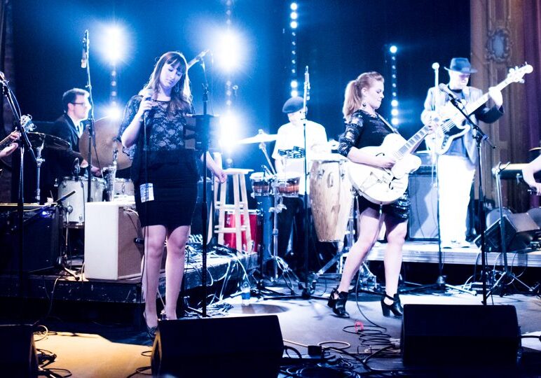 Band performing on stage with vibrant lighting.