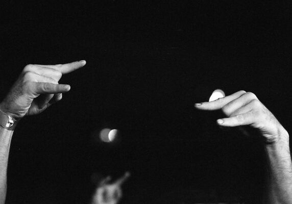 Hands gesturing against dark background.