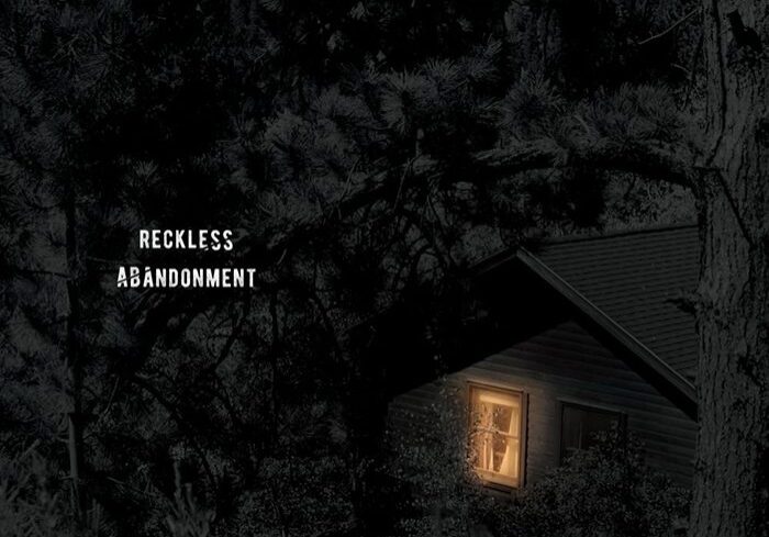 Cabin with light in dark forest.