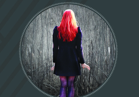 Woman standing in forest, red hair.