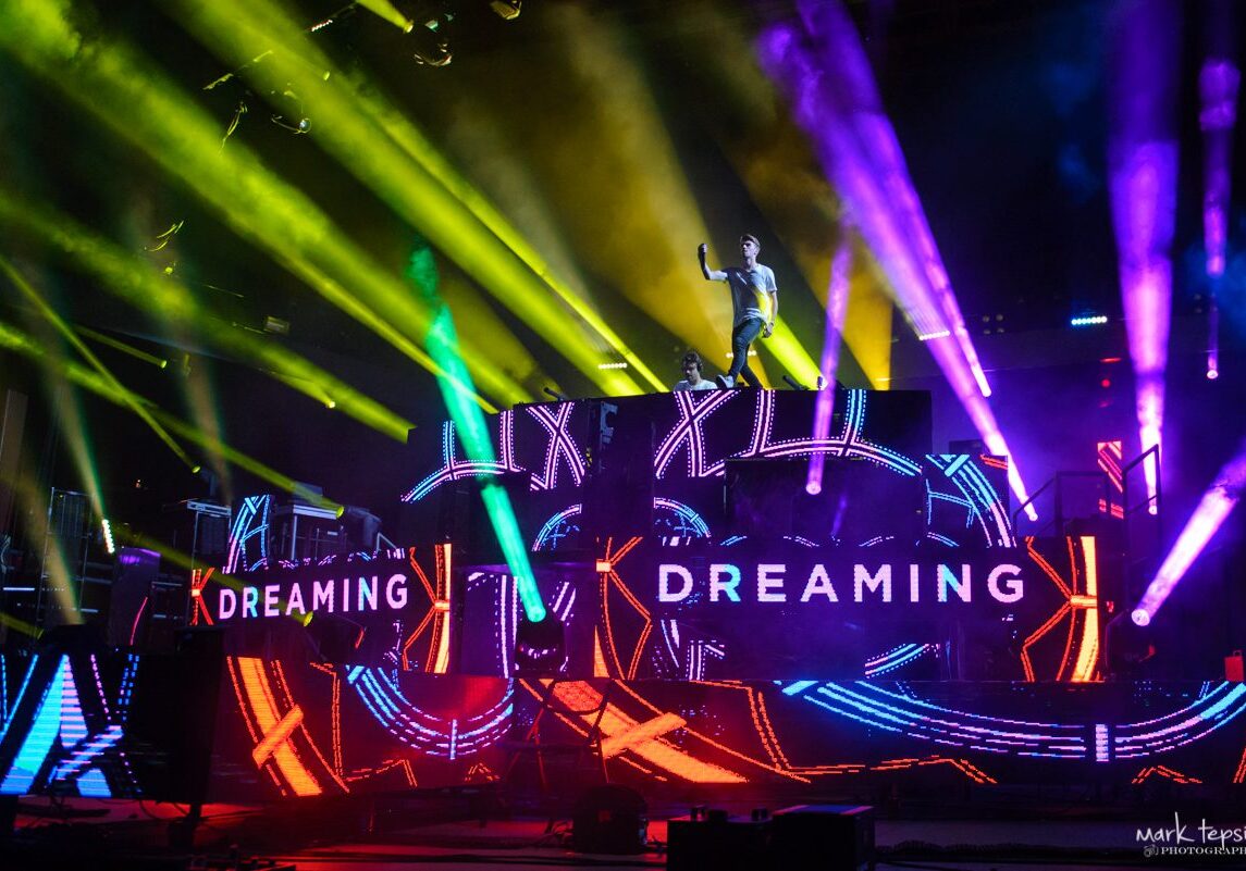 DJ performing on colorful stage with lights.