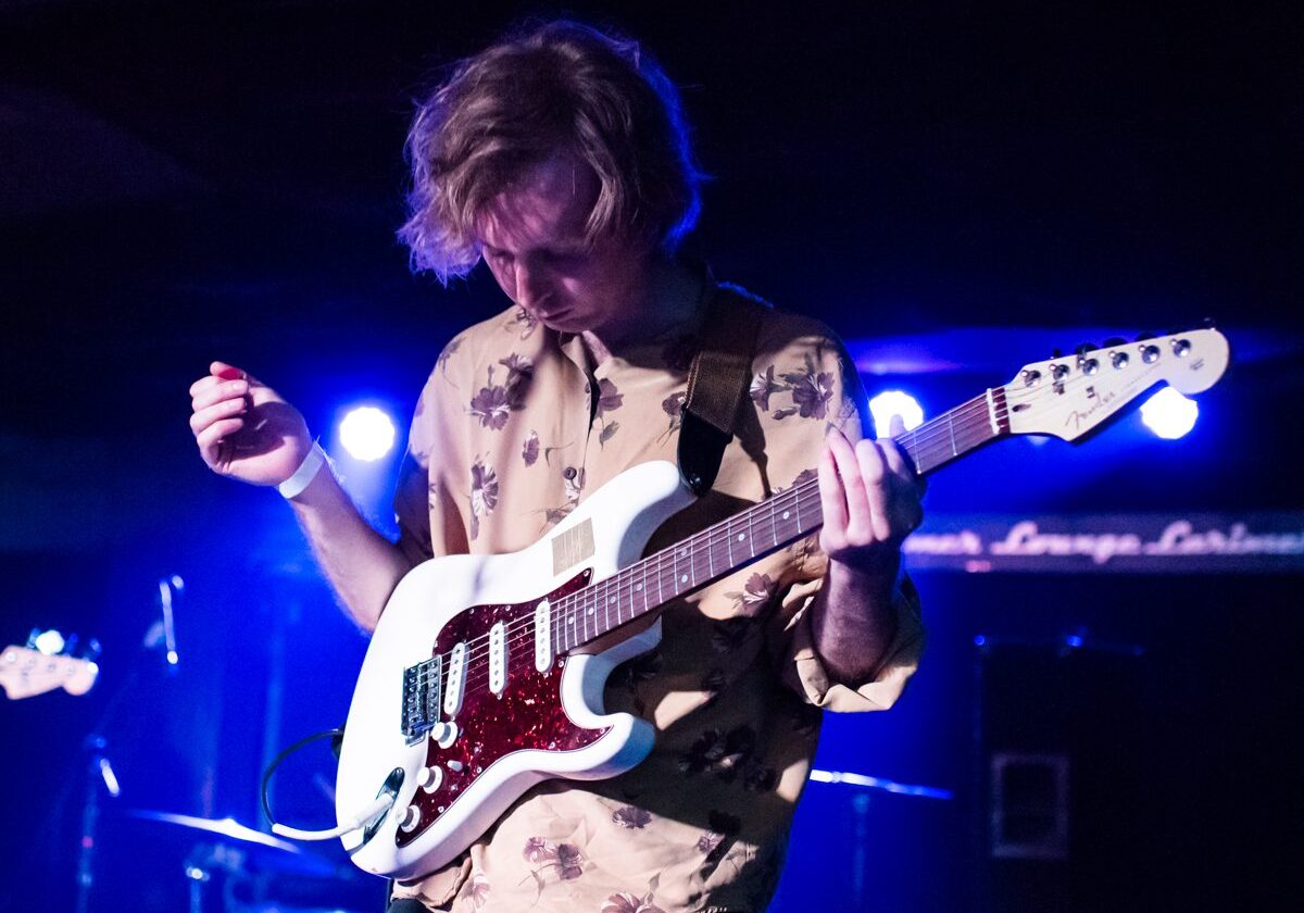 Guitarist performing on stage with lights.