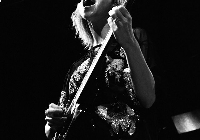Musician singing and playing guitar on stage.