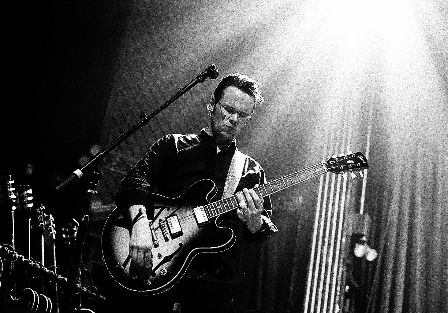 Musician playing guitar on stage, dramatic lighting.