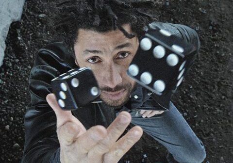 Person throwing black dice upward, artistic angle.