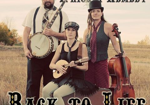 Three musicians in a field with instruments.