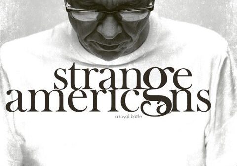 Man wearing "Strange Americans" t-shirt, looking down.