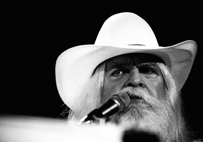 Man in white hat singing on stage.