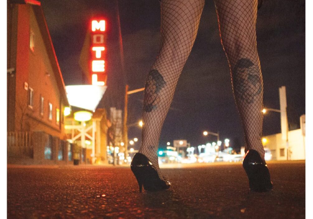 Legs in fishnets near a motel sign.