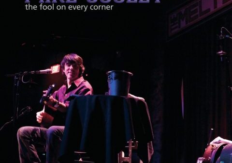 Musician performing on stage with guitar.