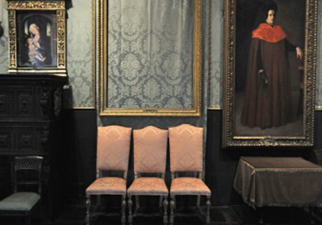 Room with framed portraits and chairs.