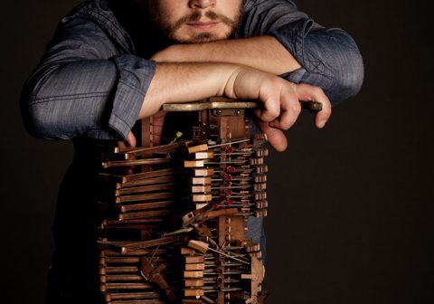 Man leaning on a wooden structure thoughtfully.