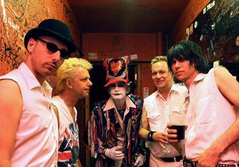 Band posing in graffiti-covered backstage area.