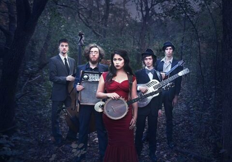 Band posing in forest with instruments.