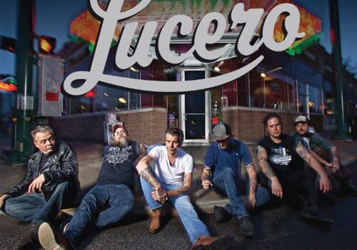 Band sitting outside diner, "Lucero" sign above.