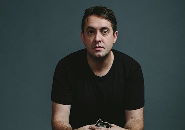 Man sitting against a dark background.
