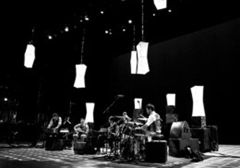 Band performing on stage with hanging lights.
