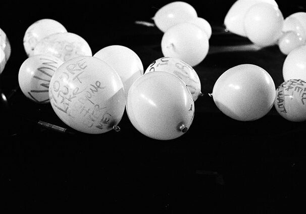 White balloons with handwritten messages on floor.