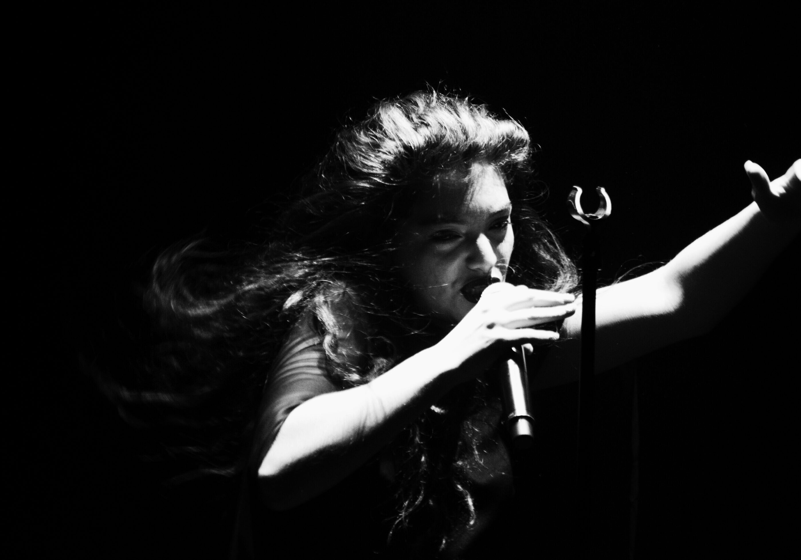Singer performing passionately in dramatic lighting.