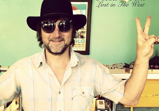 Man in sunglasses and hat making peace sign.