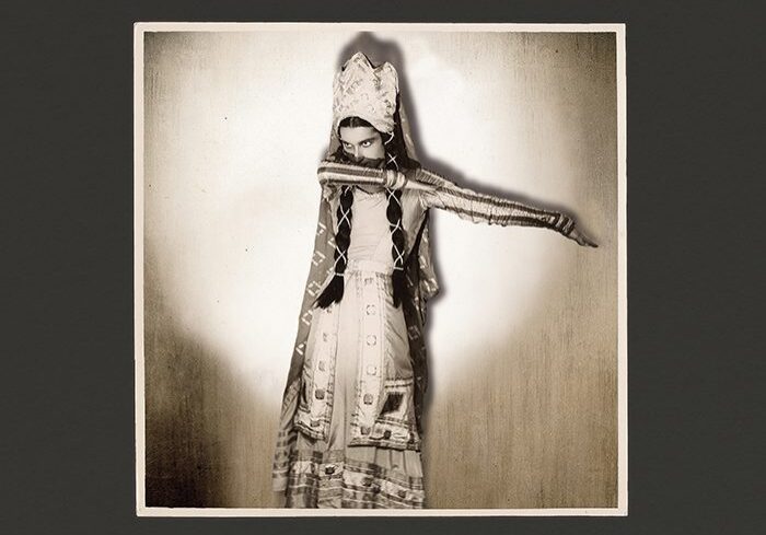Person in elaborate costume with arm extended.