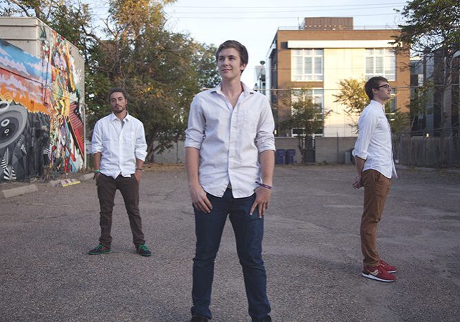 Three men standing in urban outdoor setting.