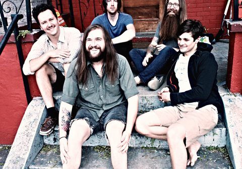 Five people sitting on outdoor steps, smiling.