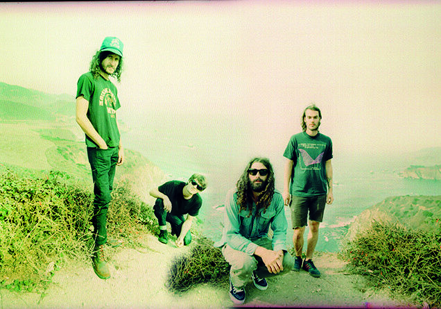 Four people posing on a scenic hill.