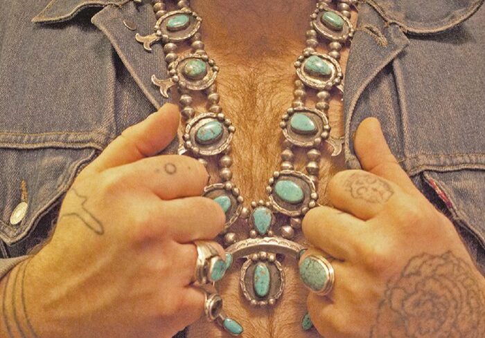 Man wearing turquoise jewelry and denim jacket.