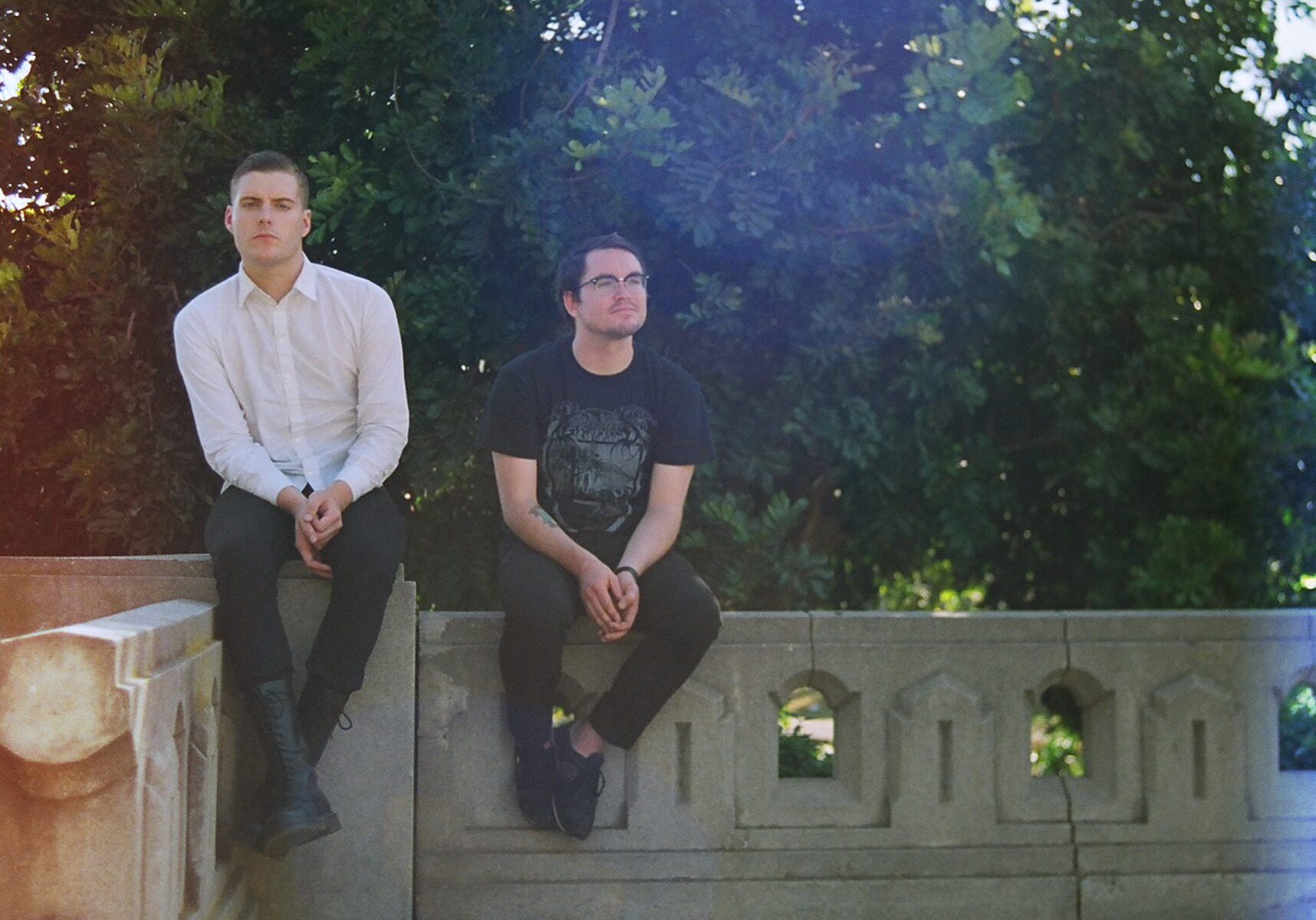 Two people sitting on a stone railing.