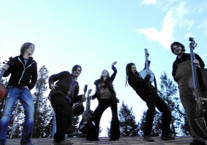 Band posing with instruments under blue sky.
